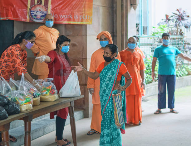 Group of volunteers and monks of Ramakrishna Mission (Golpark) wearing traditional saffron dresses, donating everyday essential foods to poor & needy people. Plastic pouch of raw foods are visible on desk. 

Photo taken at Ramakrishna Mission Institute of Culture, Golpark, Kolkata on 05/05/2020. During coronavirus lockdownin city.